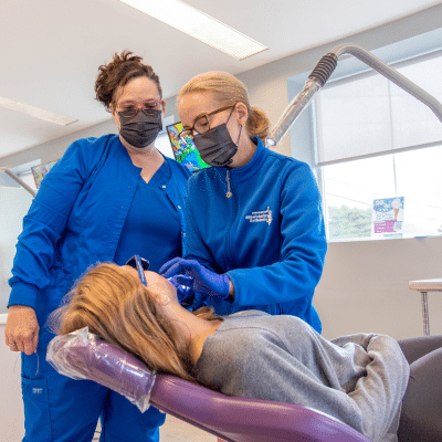 Orthodontist and assistant working on a little girl's teeth, representing silver diamine fluoride