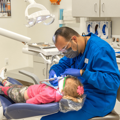 Dentist working on a little girl's teeth, representing dental x-rays