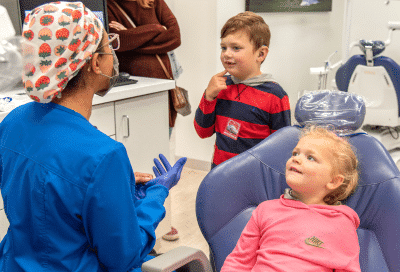 Mom and kids in the dentist office, talking to dentist, representing when should my child see the orthodontist