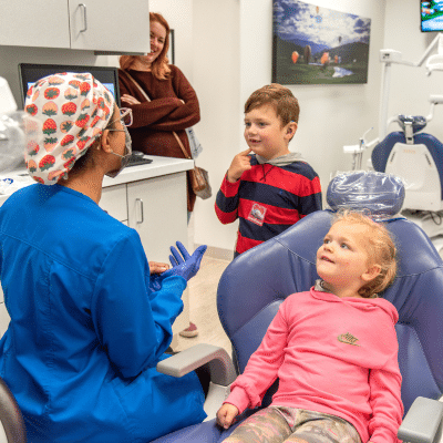 Mom and kids in the dentist office, talking to dentist, representing when should my child see the orthodontist