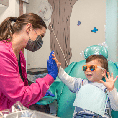 Little boy wearing sunglasses giving team member a high five, representing foods to embrace and avoid for cavity prevention