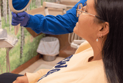 Patient looking in a mirror at her orthodontic treatment in connecticut at commerce park children’s dentistry & orthodontics