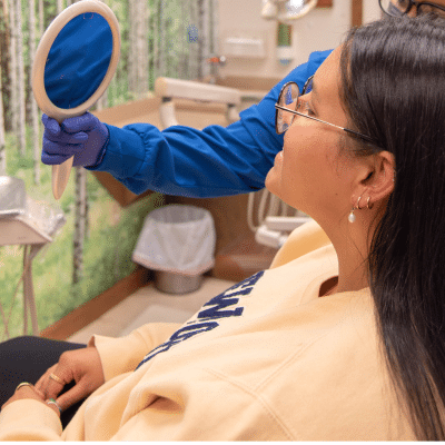 Patient looking in a mirror at her orthodontic treatment in connecticut at commerce park children’s dentistry & orthodontics