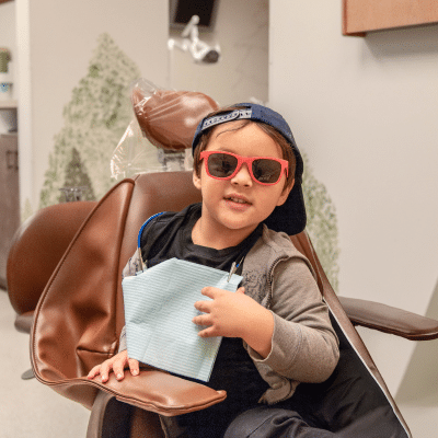 Little boy wearing red sunglasses at commerce park children’s dentistry & orthodontics, representing how to make dental visits fun for children