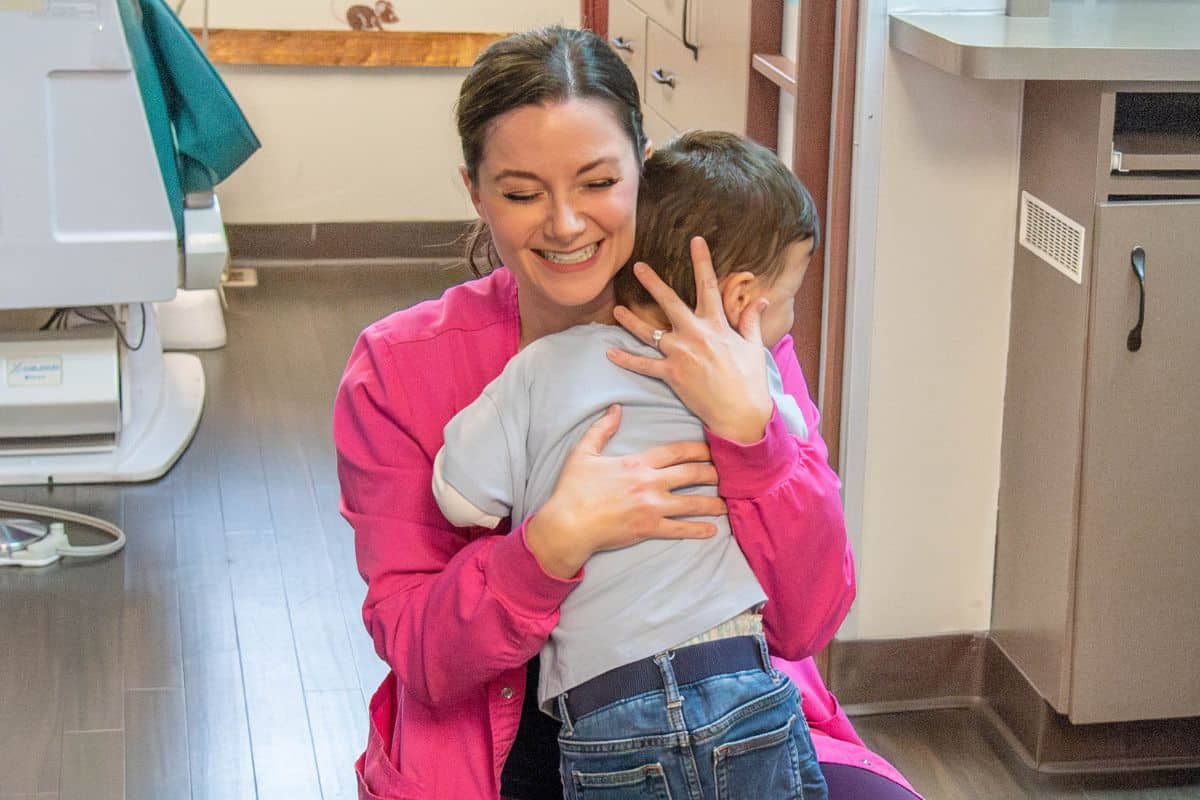 Dental hygienist hugging a young patient during a caring pediatric dental visit