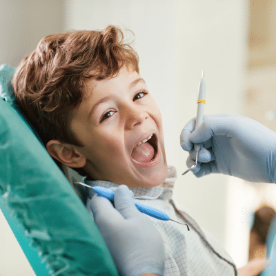 Child smiling while sitting in dental chair at the dentist, representing personalized scheduling for special needs dentistry