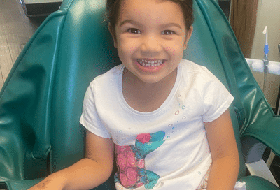 Little girl smiling whle sitting in a dental chair at commerce park children’s dentistry & orthodontics, representing braces for kids