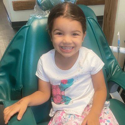 Little girl smiling whle sitting in a dental chair at commerce park children’s dentistry & orthodontics, representing braces for kids